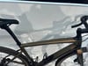 Ein goldenes Fahrrad mit schwarzem Sattel und Lenker vor weißem Hintergrund.