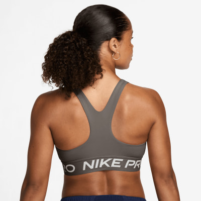 Eine Frau in einem dunkelgrauen Nike Pro Sport-BH mit Pferdeschwanz.
