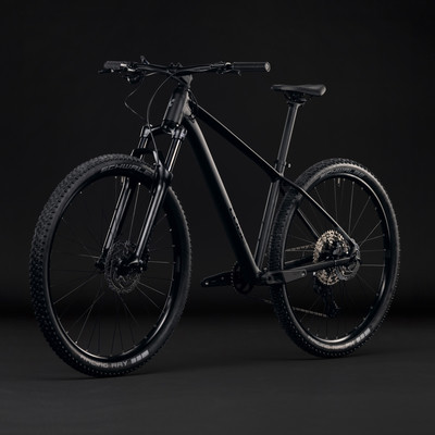 Schwarzes Mountainbike mit Federung und Scheibenbremsen vor dunklem Hintergrund.