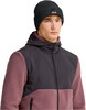 Ein Mann in einer schwarzen Mütze und einer rosa Fleecejacke mit dunkler Kapuze.