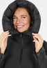 Eine Frau in einer schwarzen Daunenjacke mit Kapuze lächelt.