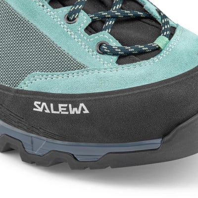 Detail eines Salewa-Schuhs mit Logo auf einem schwarzen Gummiband und grauen Schnürsenkeln. Detail eines Salewa-Schuhs mit Logo auf einem schwarzen Gummiband und grauen Schnürsenkeln.