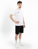 Ein Mann in einem weißen T-Shirt und schwarzen Shorts steht vor einem weißen Hintergrund.