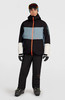 Ein Mann in einer Skijacke und Hose mit Skischuhen und Brille.