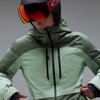 Eine Skifahrerin in einer grünen Jacke und Oakley-Brille blickt nach unten.