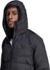 Ein Mann in einer schwarzen Daunenjacke mit Kapuze und Adidas-Logo auf der Brust.