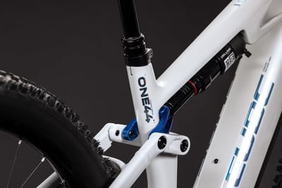 Detail des Hinterbaus eines weißen Mountainbikes mit Dämpfer und Federung.