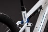 Detail des Hinterbaus eines weißen Mountainbikes mit Dämpfer und Federung.