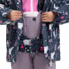 Kind in Winterjacke mit Bärendruck und lila Latzhose.