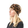 Eine Frau mit einem Leopardenmuster-Stirnband, von der Seite fotografiert.
