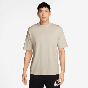 Ein Mann in einem beigen T-Shirt und schwarzen Shorts mit Nike-Logo.