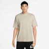 Ein Mann in einem beigen T-Shirt und schwarzen Shorts mit Nike-Logo.