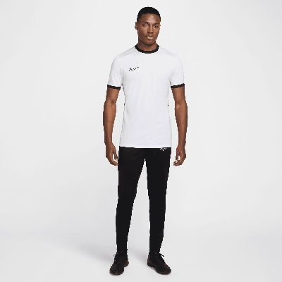 Mann in weißem T-Shirt und schwarzer Hose mit Nike-Logo. Mann in weißem T-Shirt und schwarzer Hose mit Nike-Logo.