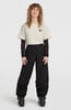 Frau in beige T-Shirt, schwarzer Skihose und Skischuhen.