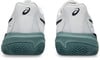 Rückansicht von weißen Tennisschuhen mit dunkelblauem Asics-Logo und grüner Sohle.