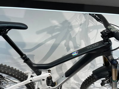 Rahmendetail eines Mountainbikes mit Regenbogenaufkleber und Markenschriftzug. Rahmendetail eines Mountainbikes mit Regenbogenaufkleber und Markenschriftzug.