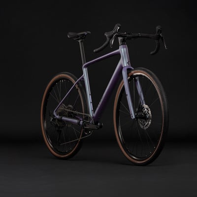 Lila Gravelbike mit braunen Reifen vor schwarzem Hintergrund. Lila Gravelbike mit braunen Reifen vor schwarzem Hintergrund.