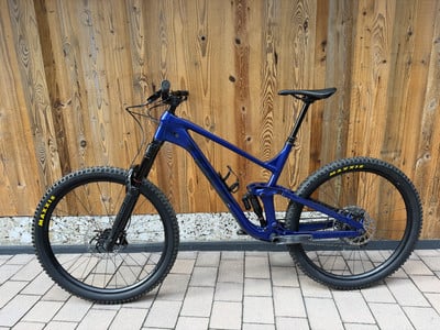 Ein blaues Mountainbike mit Federung steht vor einer Holzwand. Ein blaues Mountainbike mit Federung steht vor einer Holzwand.