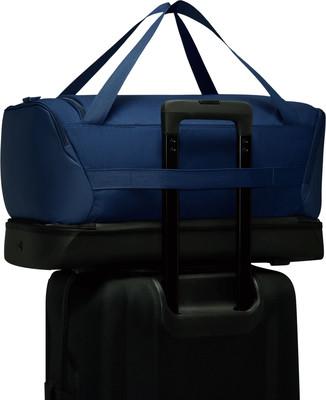 Eine blaue Reisetasche mit Trägern auf einem schwarzen Koffer. Eine blaue Reisetasche mit Trägern auf einem schwarzen Koffer.
