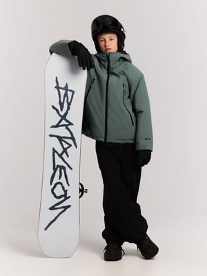 Ein Junge in Skijacke und Hose steht mit einem Snowboard. Ein Junge in Skijacke und Hose steht mit einem Snowboard.