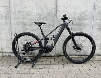 Ein graues Conway E-Bike mit schwarzen Rädern und Federung steht auf Pflastersteinen.