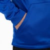 Ein Mann hat seine Hände in den Taschen eines blauen Hoodies.