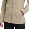 Eine beige Damenjacke mit Reißverschluss und einer Tasche, in die eine Frau ihre Hand legt.