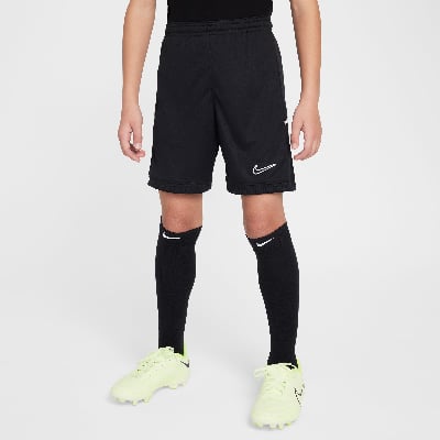 Junge in schwarzer Fußballhose mit weißem Nike-Logo und gelben Fußballschuhen.
