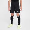 Junge in schwarzer Fußballhose mit weißem Nike-Logo und gelben Fußballschuhen.