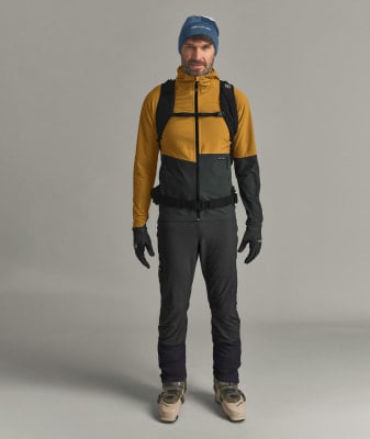 Ein Mann in Skibekleidung mit Rucksack und Skischuhen. Ein Mann in Skibekleidung mit Rucksack und Skischuhen.