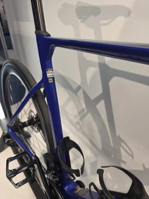 Blauer Rennradrahmen mit schwarzen Flaschenhaltern und Fahrradschatten an der Wand. Blauer Rennradrahmen mit schwarzen Flaschenhaltern und Fahrradschatten an der Wand.