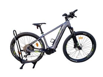 Graues E-Mountainbike auf einem Ständer vor weißem Hintergrund.