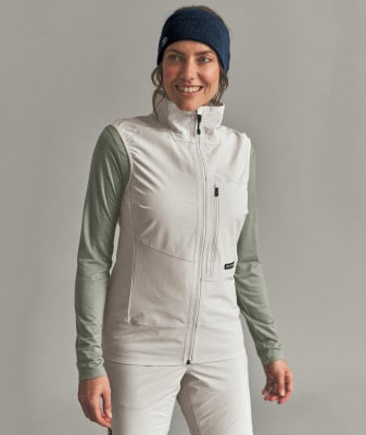 Frau in einer hellbeigen Weste und grünem Langarmshirt mit Stirnband. Frau in einer hellbeigen Weste und grünem Langarmshirt mit Stirnband.