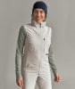 Frau in einer hellbeigen Weste und grünem Langarmshirt mit Stirnband.