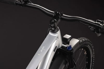 Detail der Vorderseite eines silbernen E-Bikes mit Lenker und Federung. Detail der Vorderseite eines silbernen E-Bikes mit Lenker und Federung.