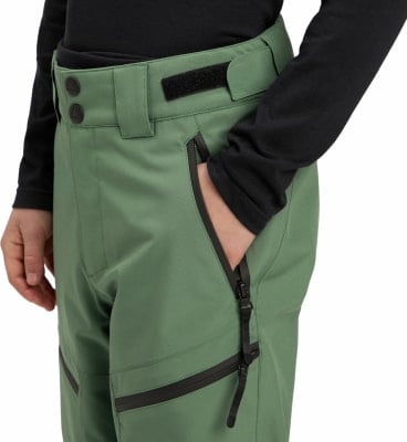 Detail einer grünen Herrenhose mit Reißverschlusstasche und Logo.