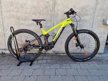 Ein gelbes Mountain-E-Bike mit schwarzen Details steht auf einem Ständer.
