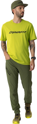 Mann in grünem Dynafit T-Shirt und Hose mit Kappe. Mann in grünem Dynafit T-Shirt und Hose mit Kappe.