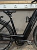 Schwarzes E-Bike mit Flaschenhalter und KTM-Logo, stehend vor Steckdosen.