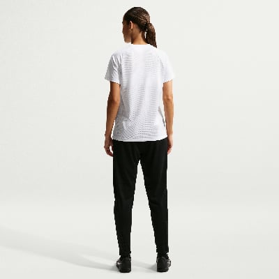 Eine Frau in einem weißen T-Shirt und schwarzer Hose steht mit dem Rücken zum Betrachter.