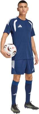 Ein Mann im dunkelblauen Fußballtrikot und Shorts hält einen Ball. Ein Mann im dunkelblauen Fußballtrikot und Shorts hält einen Ball.