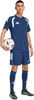 Ein Mann im dunkelblauen Fußballtrikot und Shorts hält einen Ball.