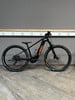 Schwarzes E-Bike mit orangefarbenen Details vor dunklem Hintergrund.