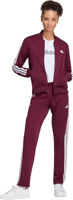 Eine Frau im burgunderroten Adidas Trainingsanzug mit weißen Streifen und Turnschuhen.