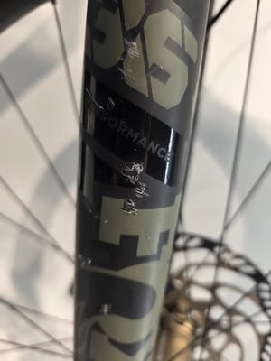 Auf der Fahrradgabel sind Kratzer und Schrammen auf schwarzer und grüner Oberfläche sichtbar. Auf der Fahrradgabel sind Kratzer und Schrammen auf schwarzer und grüner Oberfläche sichtbar.