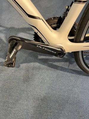 Detail eines weißen Fahrradrahmens mit schwarzen Streifen und einer Ultegra-Kurbel. Detail eines weißen Fahrradrahmens mit schwarzen Streifen und einer Ultegra-Kurbel.