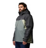 Mann in einer dunkelgrauen und hellgrauen Kapuzenjacke mit dunkelblauer Hose.