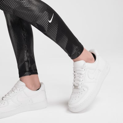 Schwarze Leggings mit weißem Nike-Logo und Punktmuster, weiße Sneaker. Schwarze Leggings mit weißem Nike-Logo und Punktmuster, weiße Sneaker.