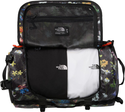 Geöffnete Tasche mit Blumenmuster, darin schwarzes und weißes T-Shirt. Geöffnete Tasche mit Blumenmuster, darin schwarzes und weißes T-Shirt.