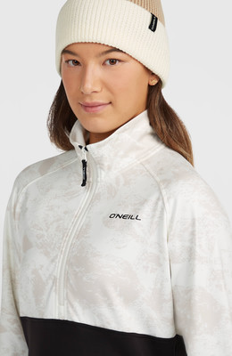 Model in einer cremefarbenen und beigen Mütze und einer weißen Jacke mit Aufdruck.